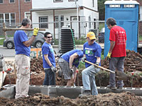 OCC employees Ammar Askari (left), Juan Marroquin (second from left), and David Permut (fourth from left) work with two other volunteers on the foundation of a home at the 2012 NeighborWorks Week site.